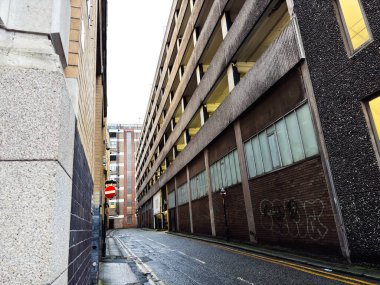 Manchester, İngiltere - 21 Ocak 2026: Manchester 'da uzun beton duvarlar, kırmızı giriş işareti ve grafiti içeren sokak manzarası.