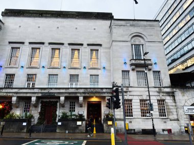 Manchester, İngiltere - 21 Ocak 2026: Manchester 'daki bir Hint restoranının şık taş cephesi işlek bir cadde boyunca mavi ışıklarla aydınlatılmış.