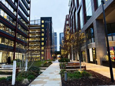 Manchester, İngiltere - 21 Ocak 2026: Yaylı ışıklar, banklar ve modern mimarinin yer aldığı şık bir Manchester New Bailey şehir merkezi sahnesi.