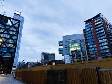 Manchester, İngiltere - 21 Ocak 2026: Manchester kentsel silueti alacakaranlıkta cam kuleler ve tuğla daireler içerir.