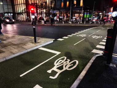 Manchester, İngiltere - 21 Ocak 2026: Manchester 'da şehir gece caddesi adanmış bisiklet yolu ve yoğun şehir hayatı.