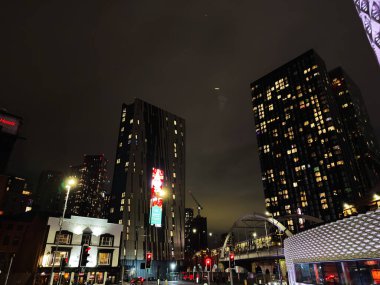 Manchester, İngiltere - 21 Ocak 2026: Manchester 'da gece manzarası gökdelenler, parlak reklam panoları, yaya geçitleri ve parlayan mimari.