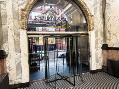 Manchester, İngiltere - 22 Ocak 2026: Manchester 'da bir mermer St. James lobisinin iç mekanı, dışarıda dönen cam bir kapı ve sokak manzarası sergiliyor.