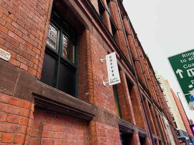 Manchester, İngiltere - 22 Ocak 2026: İşlek bir Manchester caddesi boyunca Locke Coffee Club tabelası bulunan kırmızı tuğlalı bina.