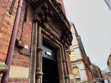 Manchester, İngiltere - 22 Ocak 2026: Tarihi mimari ve kentsel cazibe sergilenen Manchester caddesinde antika tuğla cephe ve büyük kapı önü.
