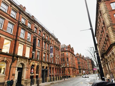 Manchester, İngiltere - 22 Ocak 2026: Kırmızı tuğlalı evler Manchester 'da bir şehir caddesini çevreleyerek kentsel yaşamı ve mimariyi yakalıyor.