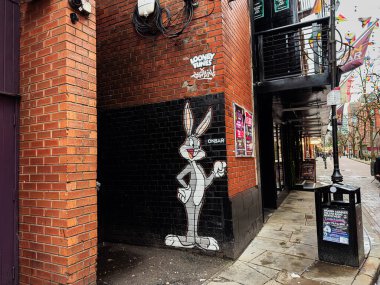 Manchester, İngiltere - 22 Ocak 2026: Çizgi film tavşanı Looney Tunes Bugs Bunny duvar resmi Manchester, İngiltere 'de bir caddenin yanında afiş ve tabela ile.