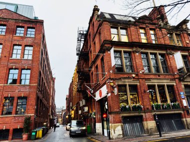 Manchester, İngiltere - 22 Ocak 2026: Manchester UK 'de tarihi tuğla binalar, tabelalar ve yağmurla yıkanmış kaldırımların yer aldığı Richmond Caddesi.