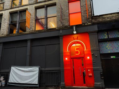 Manchester, İngiltere - 22 Ocak 2026: Vibrant Manchester 5 kırmızı bir kapı aralığı, neon kemer ve kalın beş numara.
