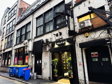 Manchester, İngiltere - 22 Ocak 2026: Manchester 'da şehir caddesi tuğla bina cepheleri, kadife bar ve sokak seviyesindeki ayrıntılar.
