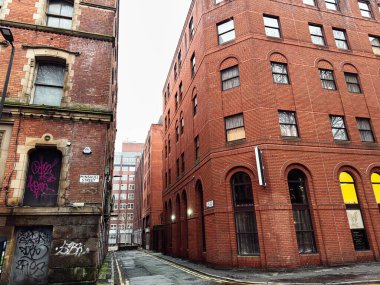 Manchester, İngiltere - 22 Ocak 2026: Manchester 'daki kırmızı tuğlalı binalar ve kemerli pencereler arasındaki dar şehir Minshull sokağı.