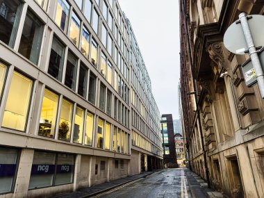 Manchester, İngiltere - 22 Ocak 2026: Cam ofis bloğuyla tarihi cephe arasında dar bir ara sokak Manchester kentsel karşıtlığını yakaladı.