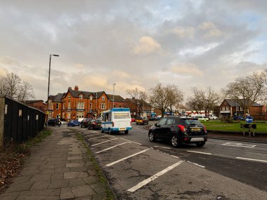 Manchester, İngiltere - 23 Ocak 2026: Manchester 'da araçlar, döner kavşak ve işlek bir caddede tarihi kırmızı tuğlalı evler.