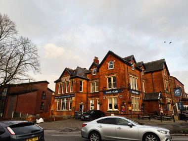 Manchester, İngiltere - 23 Ocak 2026: Manchester, İngiltere 'de kaldırımlı bir cadde boyunca ilginç kırmızı tuğlalı Nags Head barları, park halindeki arabalar.