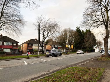 Manchester, İngiltere - 23 Ocak 2026: Manchester Caddesi 'nde evler, arabalar ve yayalar çıplak ağaçların yanında.