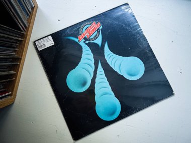 Lviv, Ukrayna - 07 Şubat 2026: Bir müzik kutusunda eskimiş, siyah bir vinil kollu, renkli mavi soyut şekiller. Manfred Mann 'in Toprak Grubu, Bülbüller ve Bombacılar 1975