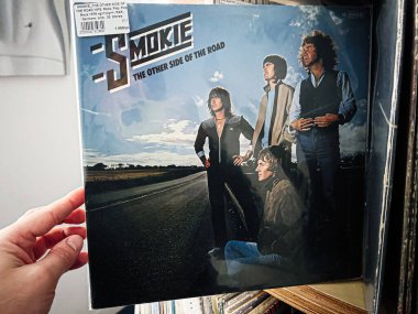 Lviv, Ukrayna - 07 Şubat 2026: Dramatik gökyüzü ve retro rock titreşimli açık bir yolda grubun yer aldığı vinil kapak. Smokie, 1979 Yolunun Diğer Tarafı