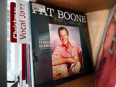 Lviv, Ukrayna - 07 Şubat 2026: Eski moda bir vinil kol Pat Boone 'u gösterir - Hit Seçim: 44 Original Recordings yanında ahşap bir plak rafı.