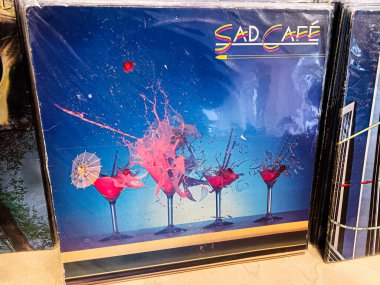 Lviv, Ukrayna - 07 Şubat 2026: Pembe süslemeli ve süslemeli mavi arka planlı barın üzerinde parlak renkli içecekler. Üzgün Kafe 1980 Vinil.