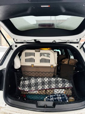 Evcil hayvan taşıyıcısı, battaniye ve çantalarla dolu bir SUV bagajını aç. Rahat bir kargo düzeneği.