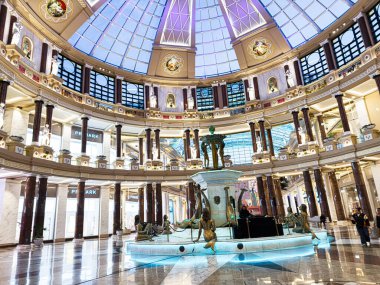 Manchester, İngiltere - 23 Ocak 2026: Merkezi bir heykel çeşmesi, mermer döşemeler, süslü sütunlar, alışveriş etkinliği ve hareketli Trafford Palazzo Atrium.