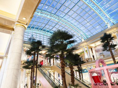 Manchester, İngiltere - 23 Ocak 2026: The Trafford Palazzo Manchester Palazzo 'da cam tavanlı, palmiye ağaçlı ve yürüyen merdivenli parlak avlu.