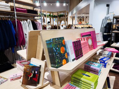 Manchester, İngiltere - 23 Ocak 2026: Manchester 'da bir giyim mağazasının içindeki modern raflardaki renkli kitap ve dergiler.