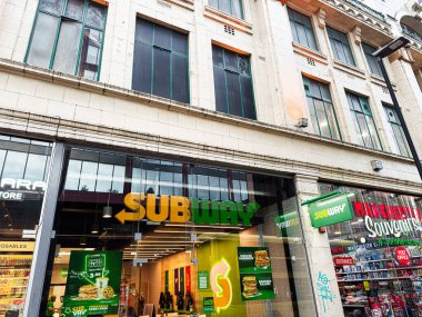 Manchester, İngiltere - 24 Ocak 2026: Manchester 'da işlek bir caddede metro mağazası, cam cephe ve parlak tabela.