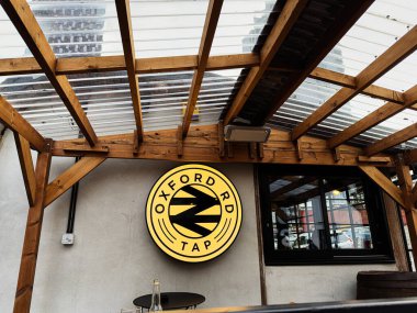 Manchester, İngiltere - 24 Ocak 2026: Manchester 'da ahşap bir pergola altında yuvarlak bir Oxford Road Tap tabelanın dış görünümü.