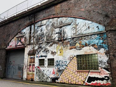 Manchester, İngiltere - 24 Ocak 2026: Renkli duvar yazıları yıpranmış tuğla cephesini pencereler, kemer ve Manchester 'da kapalı bir depo ile dolduruyor