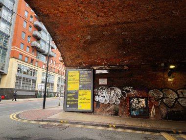 Manchester, İngiltere - 24 Ocak 2026: Manchester 'da bir tuğla Gt Marlborough Caddesi tüneli, kalın posterler, duvar yazıları ve çağdaş apartman bloklarının yer aldığı şehir sahnesi.