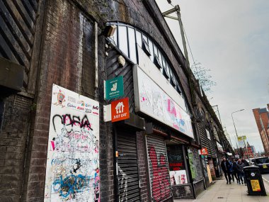 Manchester, İngiltere - 24 Ocak 2026: Grafiti ve Loco Express hamburgerleri ile dolu Manchester caddesi yayalar kapalı dükkanların önünden geçerken paket servis levhaları.