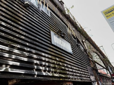 Manchester, İngiltere - 24 Ocak 2026: Manchester 'da yıpranmış Boucantier kulübü dışı; endüstriyel bir caddede paslanmış metal, grafiti ve bitki büyümesi.