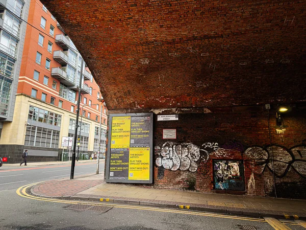 Manchester, İngiltere - 24 Ocak 2026: Manchester 'da bir tuğla Gt Marlborough Caddesi tüneli, kalın posterler, duvar yazıları ve çağdaş apartman bloklarının yer aldığı şehir sahnesi.