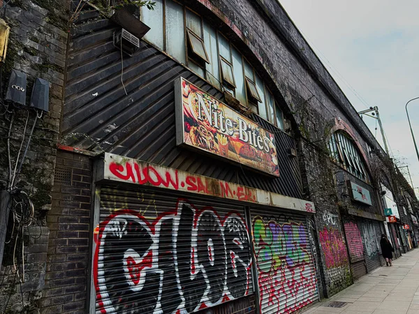 Manchester, İngiltere - 24 Ocak 2026: Graffiti, Manchester 'daki bir caddedeki fast food tabelası ve yıpranmış tuğla vitrinleriyle Gece Bitleri dükkanlarını kapladı.