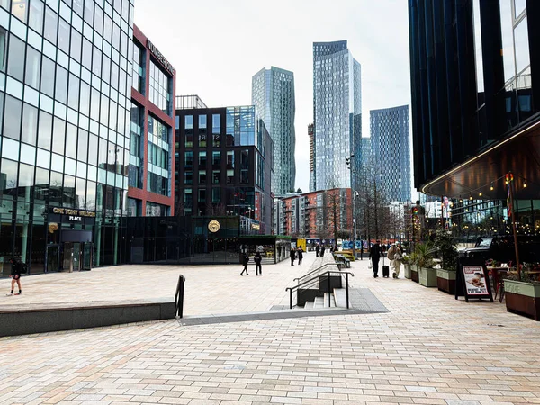 Manchester, İngiltere - 24 Ocak 2026: İnsanlar cam gökdelenler ve şık kafelerle çerçevelenmiş 1 Tony Wilson Place Manchester plazasından geçiyor.