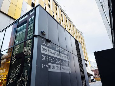 Manchester, İngiltere - 24 Ocak 2026: Camdan panelleri, kalın tabelaları ve şehir caddesi boyunca uzanan modern mimarisi olan Urban Manchester Kafe.