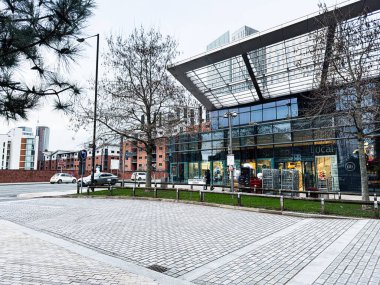 Manchester, İngiltere - 24 Ocak 2026: Manchester 'da ağaçlar ve alışveriş yapan Isabella Banks caddesinde çağdaş cam mağazaları.