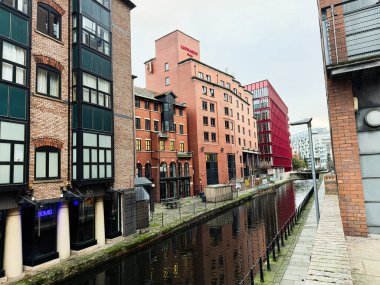 Manchester, İngiltere - 24 Ocak 2026: Manchester City Albion kanal sahnesi tuğla cepheleri, yansımalar ve çağdaş kırmızı bina.