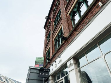 Manchester, İngiltere - 24 Ocak 2026: Manchester, İngiltere 'deki tarihi tuğla cephesi ve modern ordunun eğik bir görüntüsü.