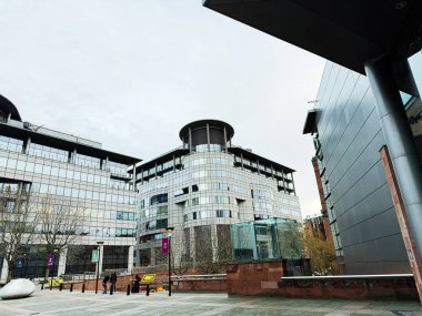 Manchester, İngiltere - 24 Ocak 2026: 100 Barbirolli Meydanı mimari sahnesi Manchester 'da cam kuleleri, açık plazası ve kentsel aktivitesi olan.