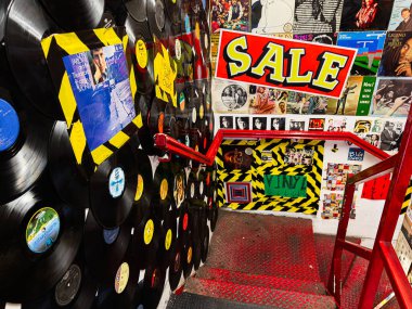 Manchester, İngiltere - 26 Ocak 2026: Renkli vinil plaklar, Manchester 'daki bir mağazanın duvarının yanında kalın bir satış tabelası ve merdiven boşluğu çiziyor.