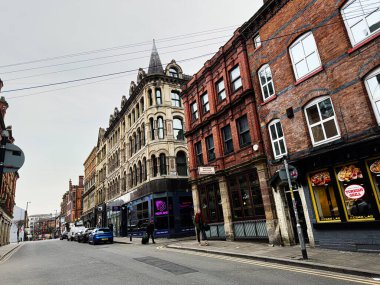 Manchester, İngiltere - 26 Ocak 2026: Manchester 'daki Quaint kentsel sabun sokağı tuğla cepheleri, mağazalar, yayalar ve hareketli dükkanların yer aldığı.