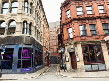 Manchester, İngiltere - 26 Ocak 2026: Tarihi binalar Manchester, İngiltere 'de parlayan bir Pikselli oyun barının yanında dar bir ara sokak çerçevesi oluşturdu.
