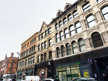 Manchester, İngiltere - 26 Ocak 2026: Manchester Thomas caddesi boyunca mağaza önü ve park etmiş araçlarla süslü taş cepheler sıralanması.