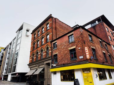 Manchester, İngiltere - 26 Ocak 2026: Manchester 'da tuğla köşe binası açık sarı Maricarmen önü ve modern beyaz komşu bloğu olan.