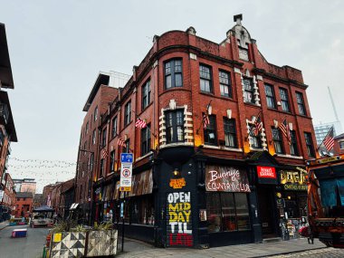 Manchester, İngiltere - 26 Ocak 2026: Bunny 's Country Club bar, neon tabelalar, bayraklar ve şehir gece hayatı içeren Manchester caddesi.