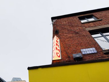 Manchester, İngiltere - 26 Ocak 2026: Manchester Edge caddesinin köşesinde neon ışıklı ve sarı cepheli tuğla bina.