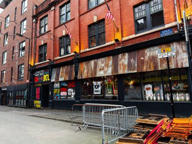 Manchester, İngiltere - 26 Ocak 2026: Tuğla Tavşan Country Club ön cephesi, paslı mağaza panelleri ve renkli bar tabelaları içeren canlı Manchester sokak manzarası.