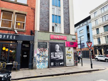 Manchester, İngiltere - 26 Ocak 2026: Vibrant Manchester Tib sokak sahnesi grafiti, dükkan önleri ve yoğun bir yol boyunca cesur tabelalar.